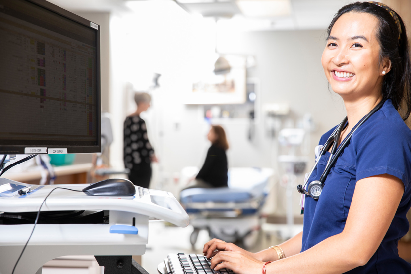 Female doctor smiling and typing on computer.