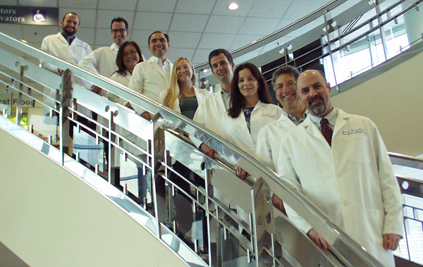 Group in white labcoats on staircase.