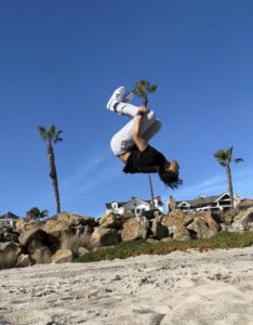Kendall doing a backflip on a beach.