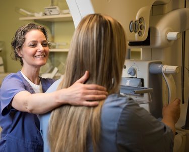 Breast imaging tech with patient.