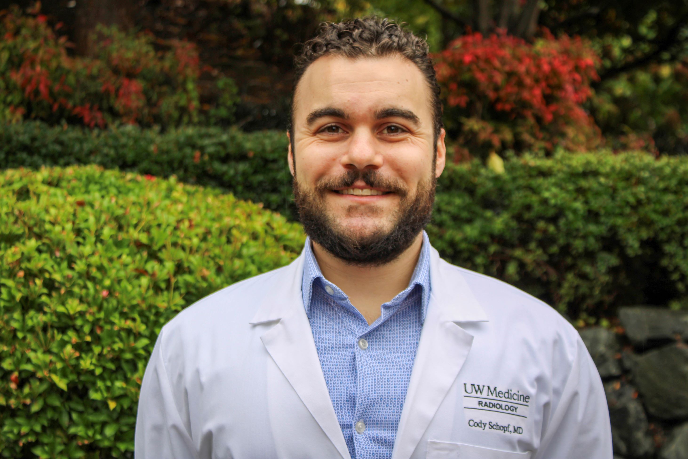 Dr. Cody Schopf smiles at the camera. he has short dark hair and a beard.