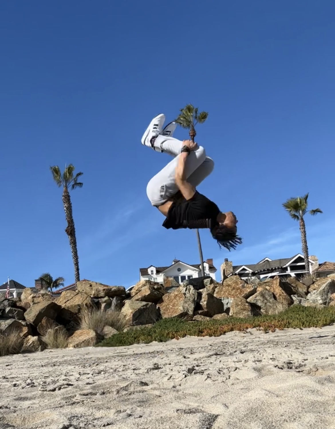 Kendall doing a backflip on a beach.